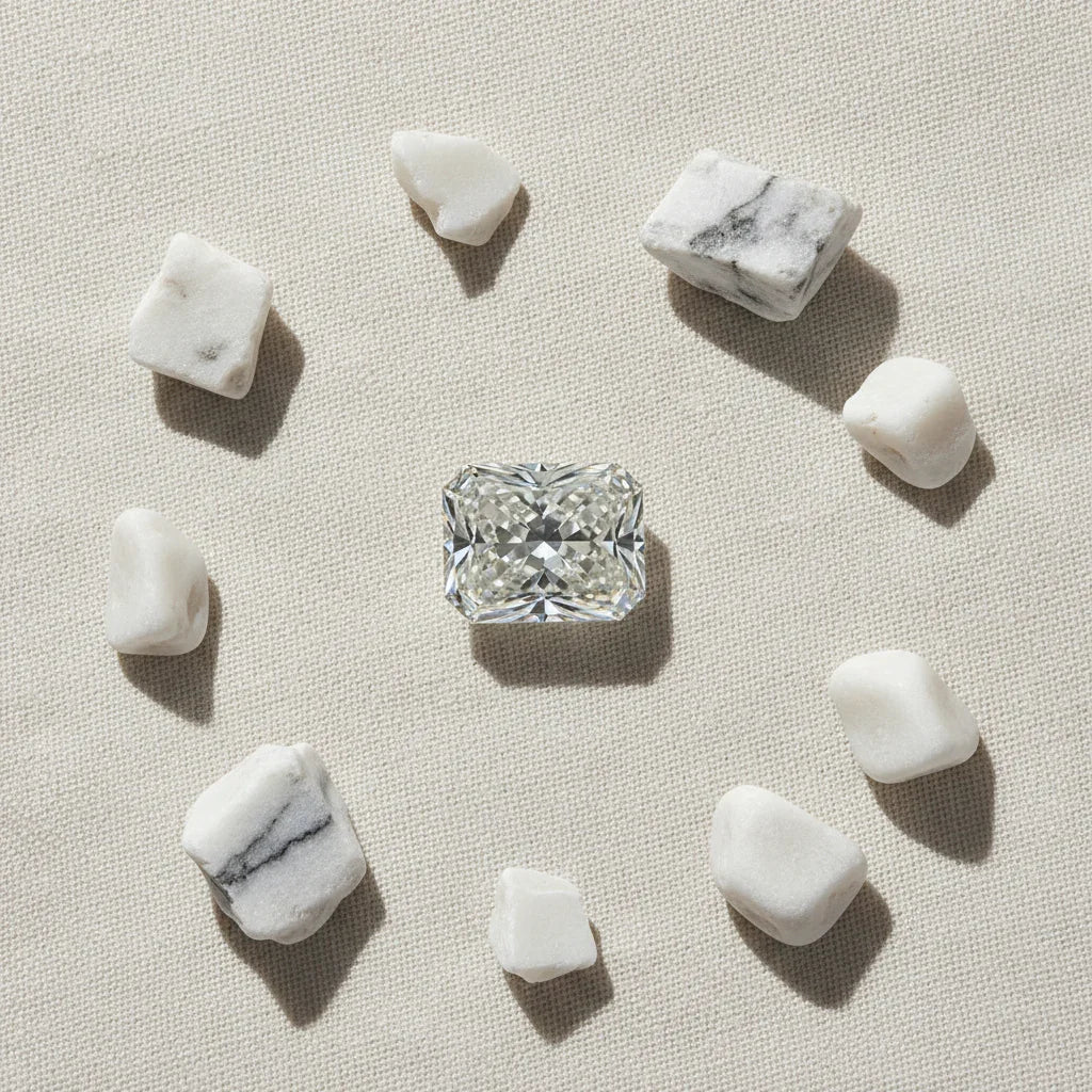 Radiant cut loose diamond surrounded by white marble stones on textured fabric, ideal for bespoke engagement rings